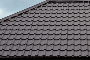 Brown roof tiles or shingles on house as background image. New overlapping brown classic style roofing material texture pattern on a actual house